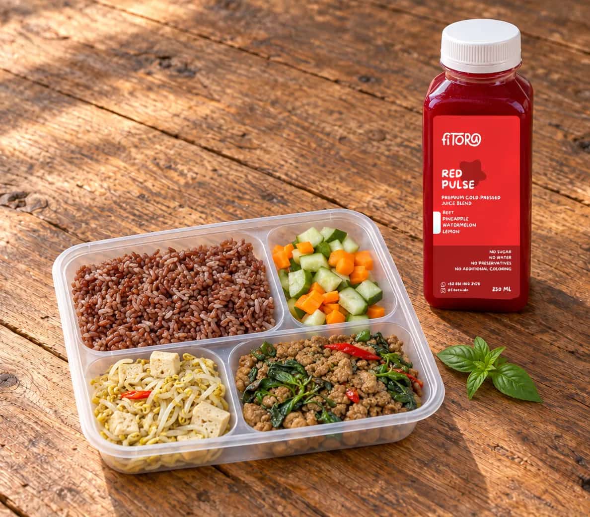Thai Chicken Basil Rice Box dan sebotol Red Pulse di meja kayu: nasi merah, ayam cincang kemangi, taoge tahu, dan acar